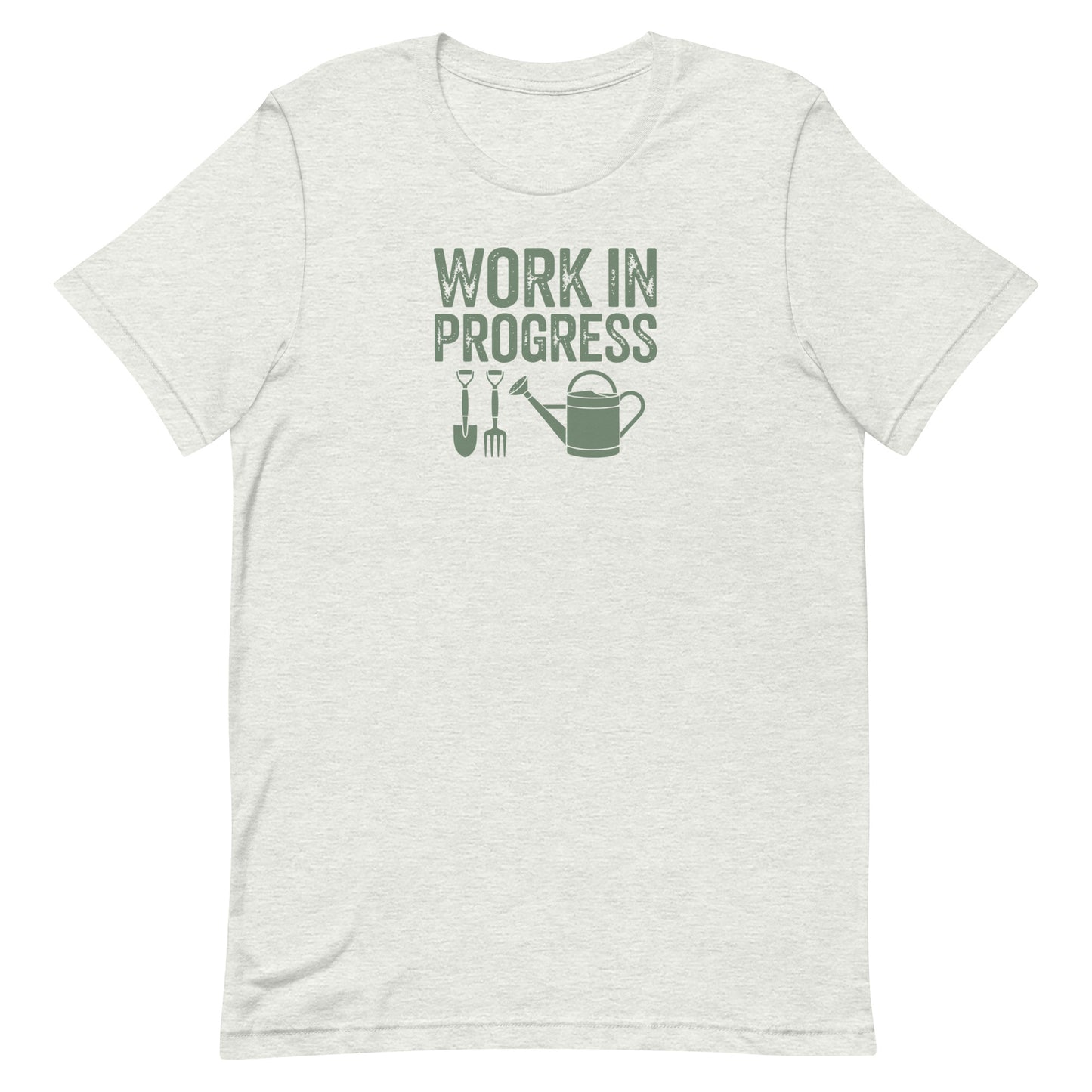 “Work in Progress” gardening graphic with shovel, pitchfork, and watering can printed in sage green on a soft pale heather gray colored crewneck t-shirt.