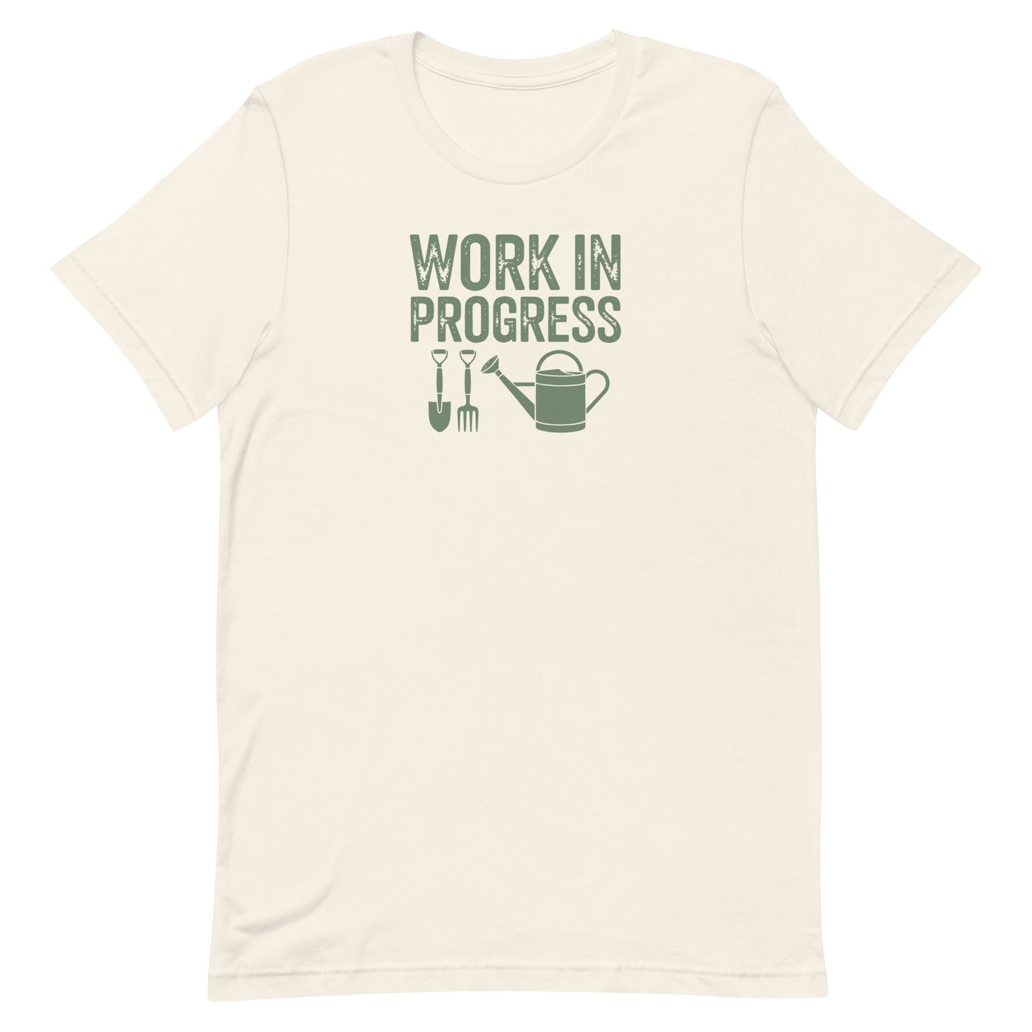 “Work in Progress” gardening graphic with shovel, pitchfork, and watering can printed in sage green on a soft off-white cream colored crewneck t-shirt.