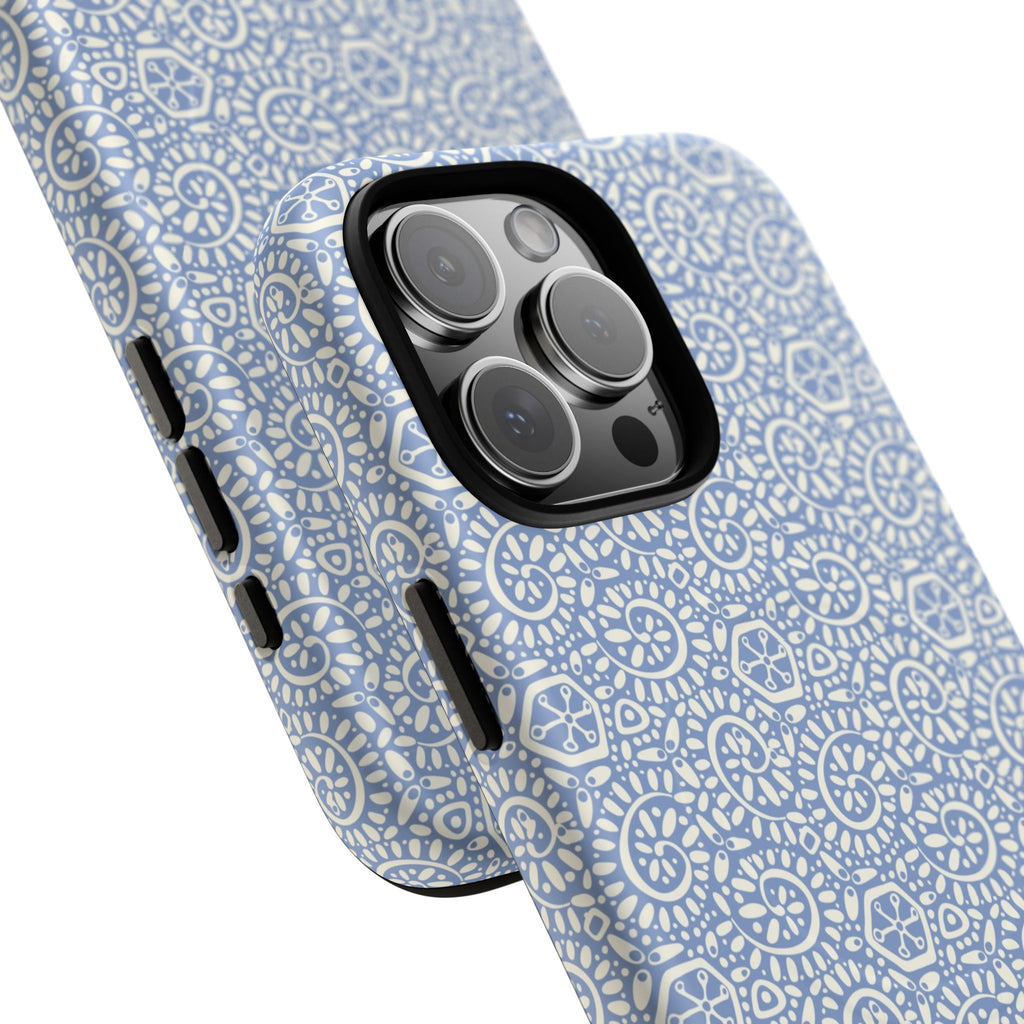 Canto Swirls Mist MagSafe iPhone 16 Pro Max Glossy Case — angled view showing slim profile; periwinkle blue folk-art medallion pattern of radiating white circular motifs, dot clusters, and geometric centers