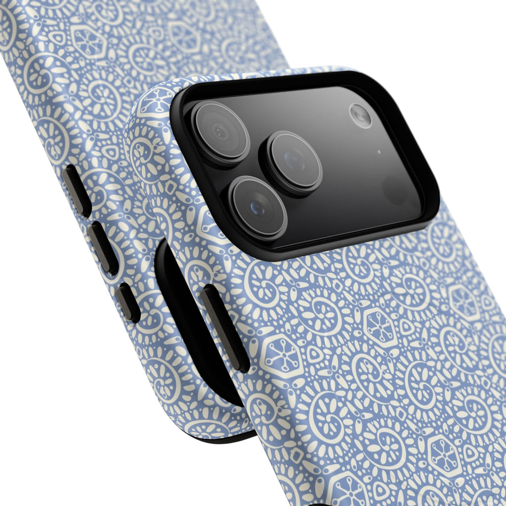 Canto Swirls Mist MagSafe iPhone 17 Pro Max Glossy Case — angled view showing slim profile; periwinkle blue folk-art medallion pattern of radiating white circular motifs, dot clusters, and geometric centers