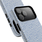 Canto Swirls Mist MagSafe iPhone 17 Pro Max Glossy Case — angled view showing slim profile; periwinkle blue folk-art medallion pattern of radiating white circular motifs, dot clusters, and geometric centers