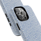 Canto Swirls Mist iPhone 16 Pro Max Glossy Case — angled view showing slim profile; periwinkle blue folk-art medallion pattern of radiating white circular motifs, dot clusters, and geometric centers