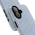 Canto Swirls Mist MagSafe iPhone 17 Glossy Case — angled view showing slim profile; periwinkle blue folk-art medallion pattern of radiating white circular motifs, dot clusters, and geometric centers