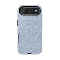 Canto Swirls Mist iPhone 17 Matte Case — periwinkle blue hard case covered in an intricate folk-art medallion pattern of radiating white circular motifs, dot clusters, and geometric centers