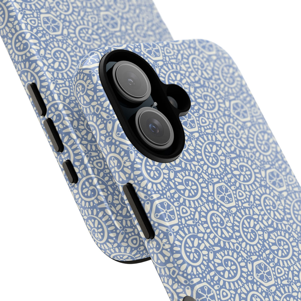 Canto Swirls Mist iPhone 17 Glossy Case — angled view showing slim profile; periwinkle blue folk-art medallion pattern of radiating white circular motifs, dot clusters, and geometric centers