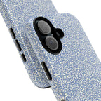 Canto Swirls Mist iPhone 17 Glossy Case — angled view showing slim profile; periwinkle blue folk-art medallion pattern of radiating white circular motifs, dot clusters, and geometric centers