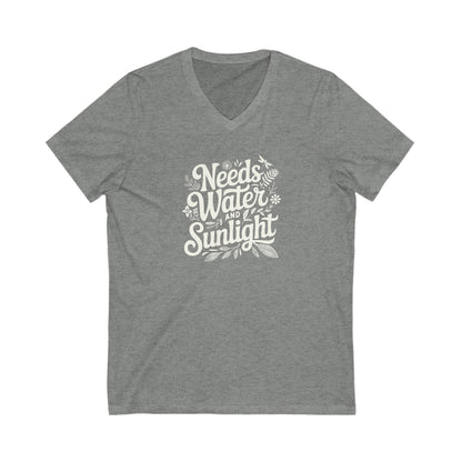 Medium Gray heather colored vneck t-shirt with white words that say 'Needs Water and Sunlight' in script style text with dragonfly, flower and leaf illustrations around the words.