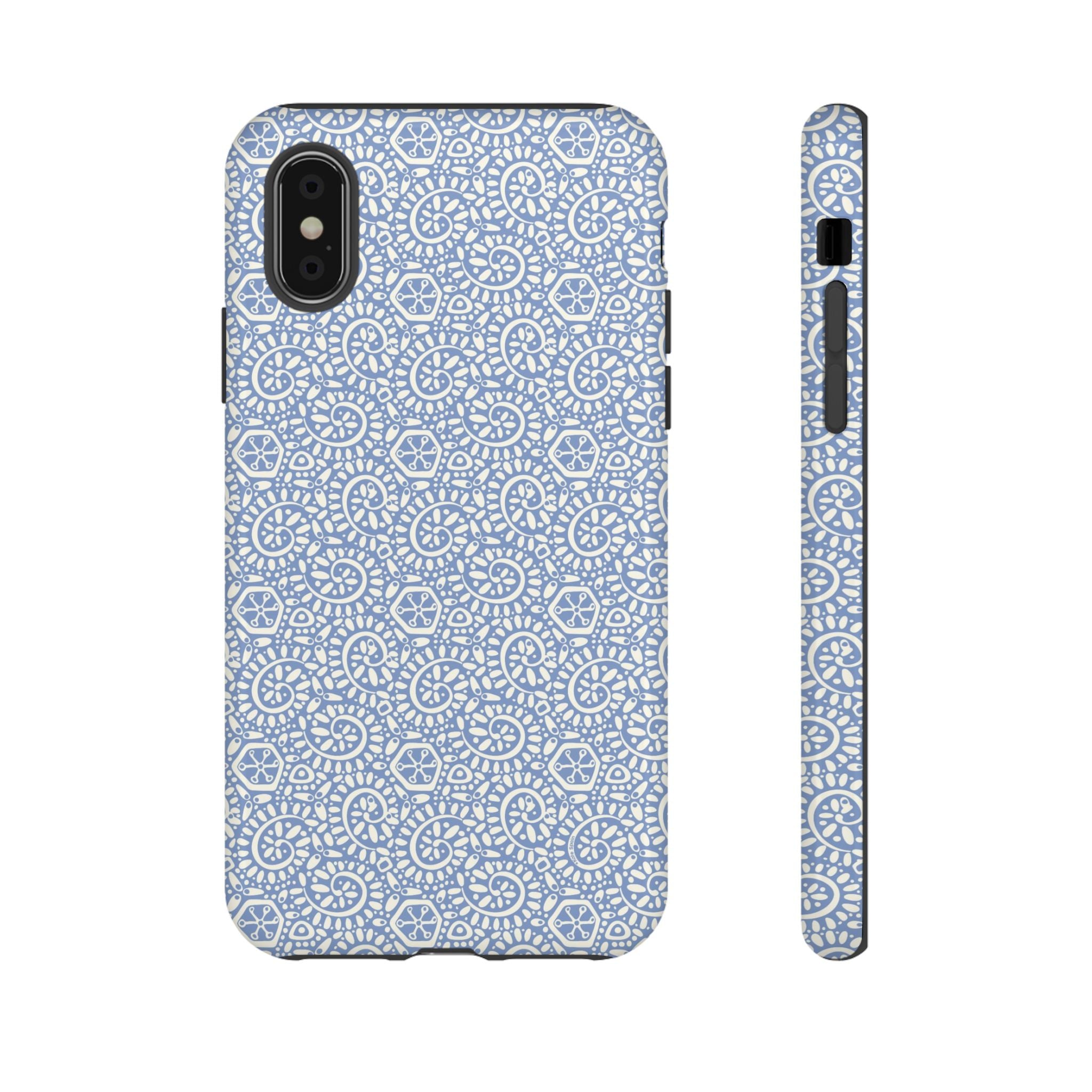 Canto Swirls Mist iPhone XS Glossy Case — periwinkle blue hard case covered in an intricate folk-art medallion pattern of radiating white circular motifs, dot clusters, and geometric centers