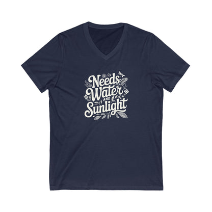 Navy Blue colored vneck t-shirt with white words that say 'Needs Water and Sunlight' in script style text with dragonfly, flower and leaf illustrations around the words.