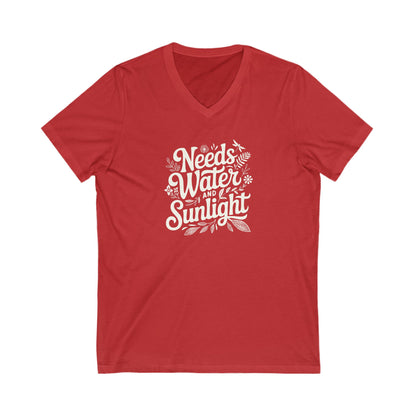 Red colored vneck t-shirt with white words that say 'Needs Water and Sunlight' in script style text with dragonfly, flower and leaf illustrations around the words.