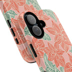 Hibiscus Coral iPhone 17 Glossy Case — angled view showing slim profile; blush pink case with coral red hibiscus flowers and teal-green leaves in bold botanical linework