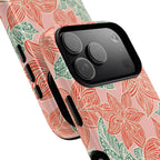 Hibiscus Coral MagSafe iPhone 17 Pro Max Glossy Case — angled view showing slim profile; blush pink case with coral red hibiscus flowers and teal-green leaves in bold botanical linework