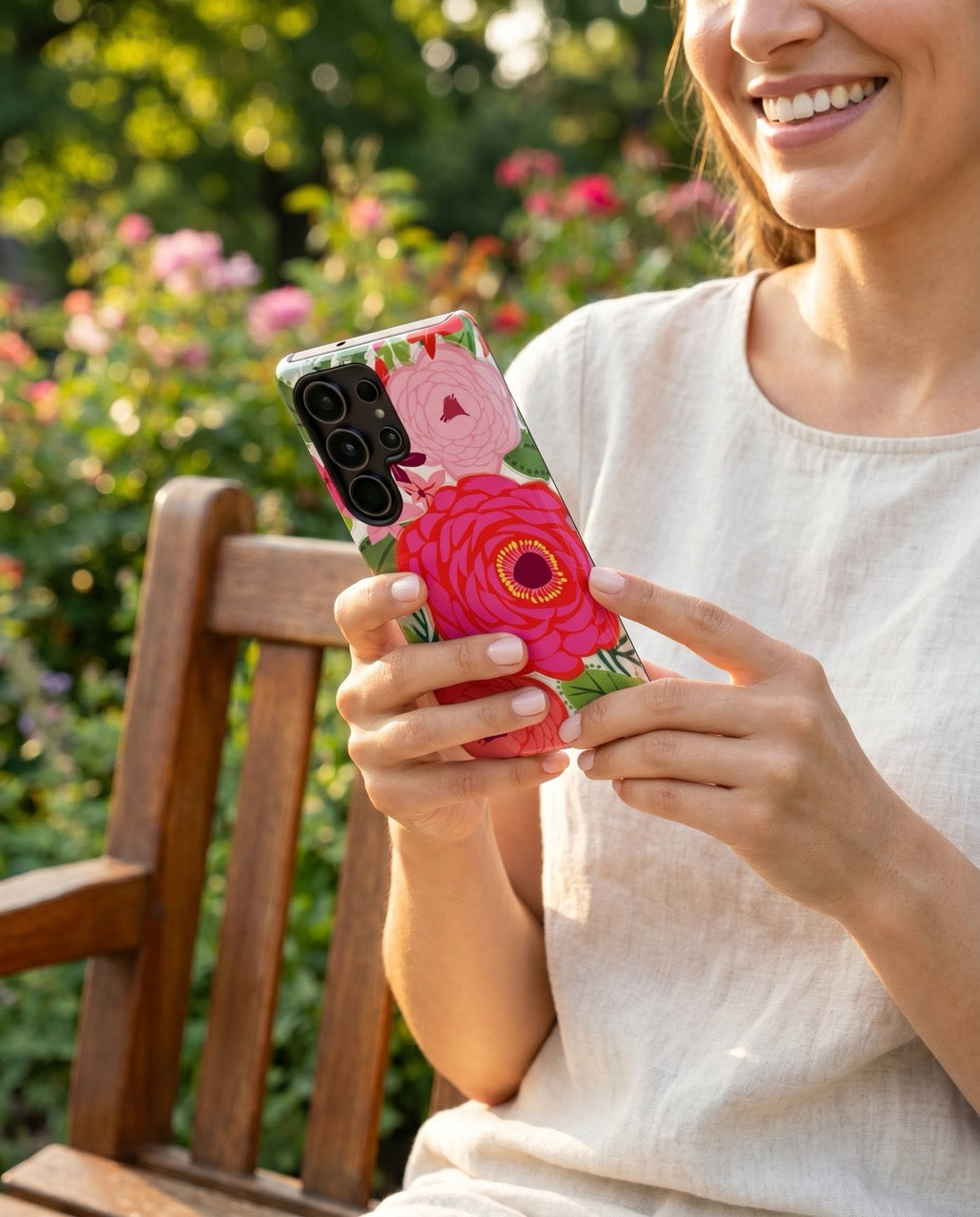 Person in a garden holding a Samsung Galaxy S26 Ultra phone with a Bloomerie fuchsia floral case by floriori