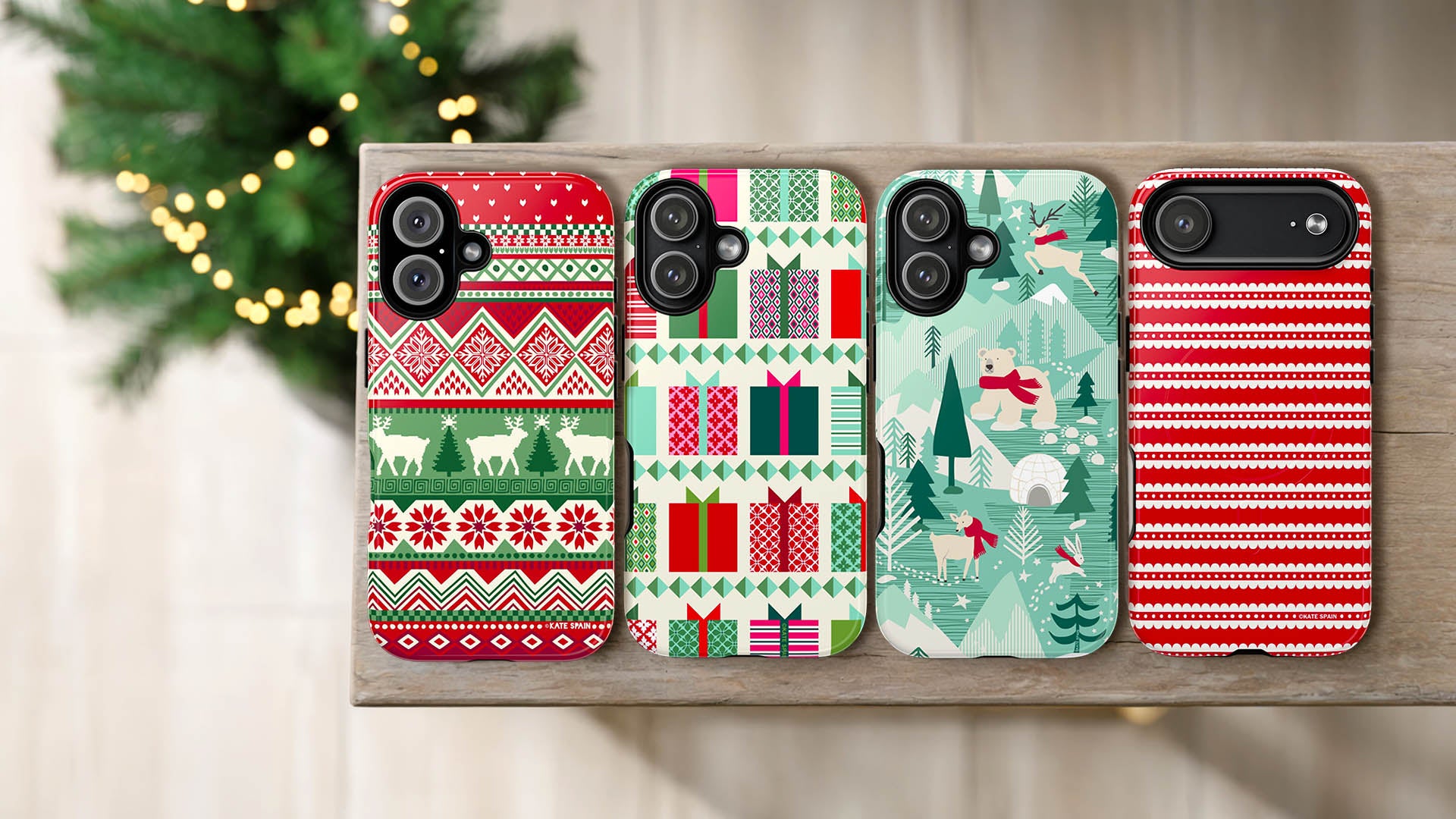 Four Christmas-themed phone cases on a wooden surface with a blurred background