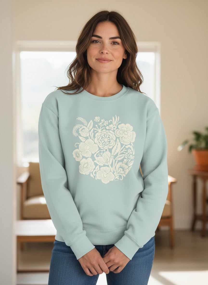 Woman wearing a light blue sweatshirt with floral design in a room.