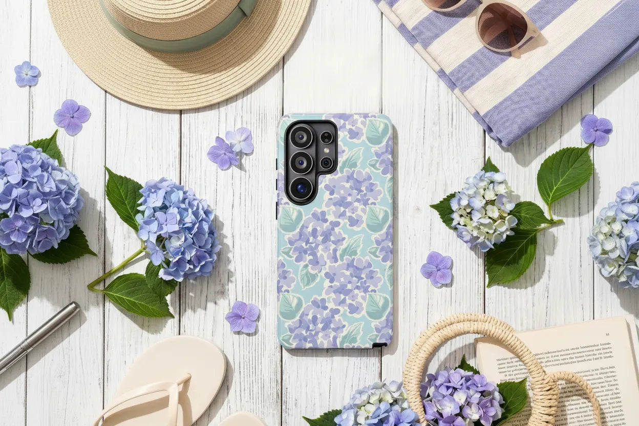 Phone case with floral design on a wooden surface with flowers and a hat.