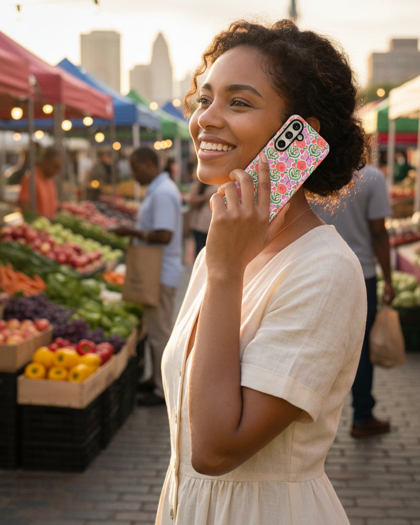 Woman holding a samsung galaxy s26 phone with a floral case in an urban farmer's market