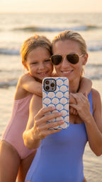 Seashells MagSafe iPhone Case – lifestyle shot of mother and daughter in swimsuits at the beach holding the Seashells MagSafe iPhone 16 Pro Max case | periwinkle, cream scallop shell print MagSafe compatible, dual-layer protection