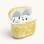 floriori AirPods case with sophisticated and energetic hand painted flower silhouettes. yellow floral on a cream glossy background. open with earbuds.