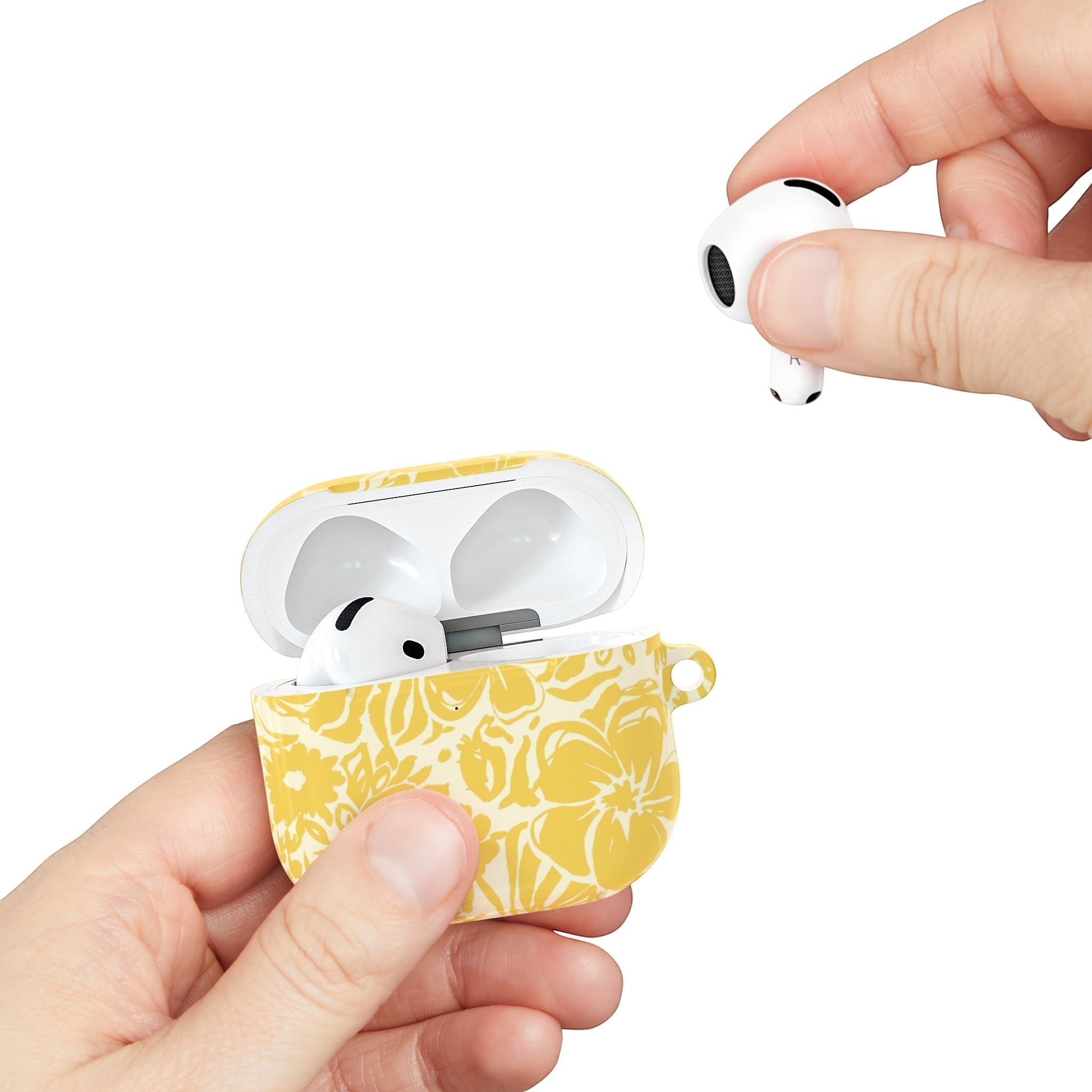 floriori AirPods case with sophisticated and energetic hand painted flower silhouettes. yellow floral on a cream glossy background. showing scale with earbuds.
