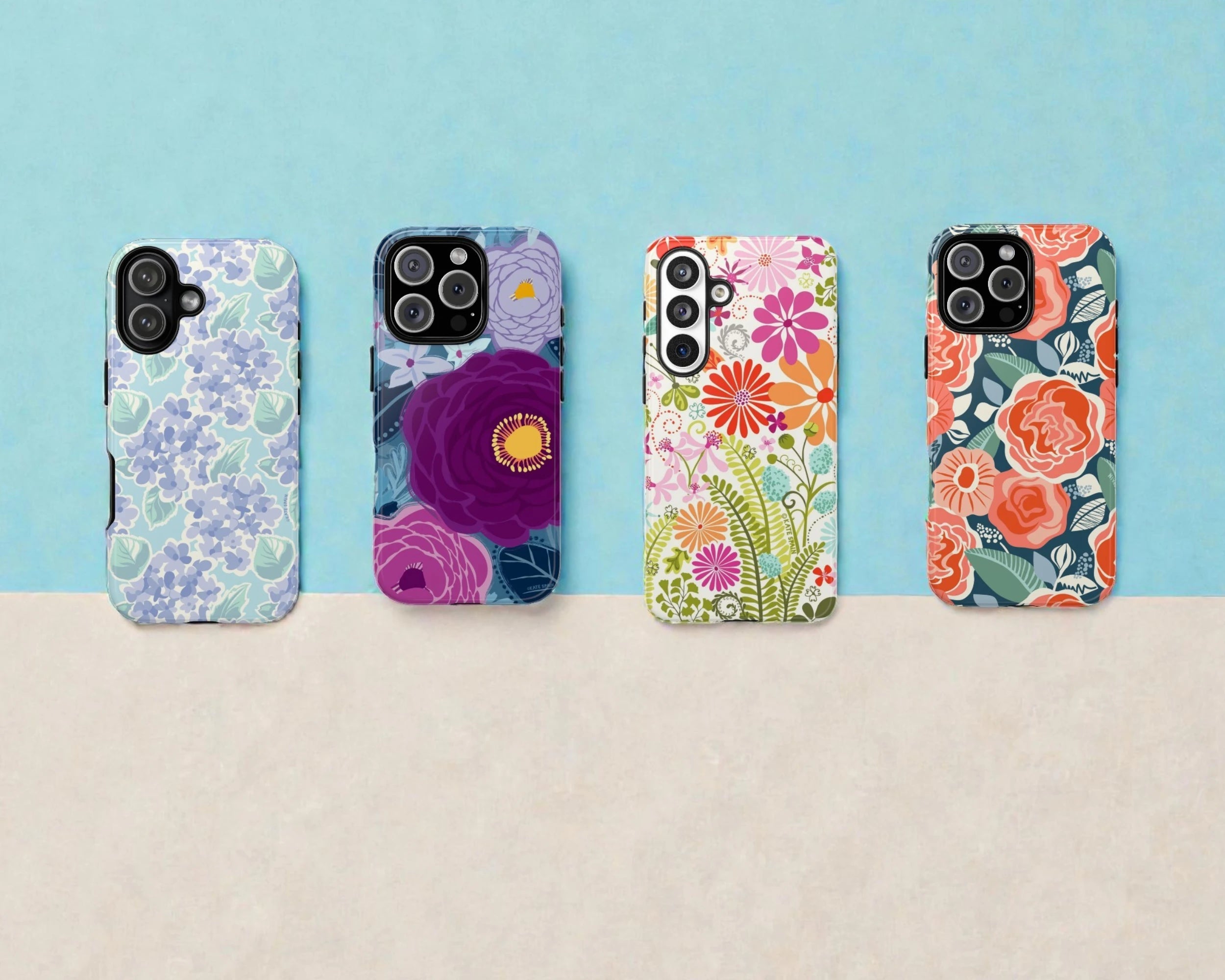 Four floral iphone and Samsung Galaxy phone cases on a beige surface with a blue background.
