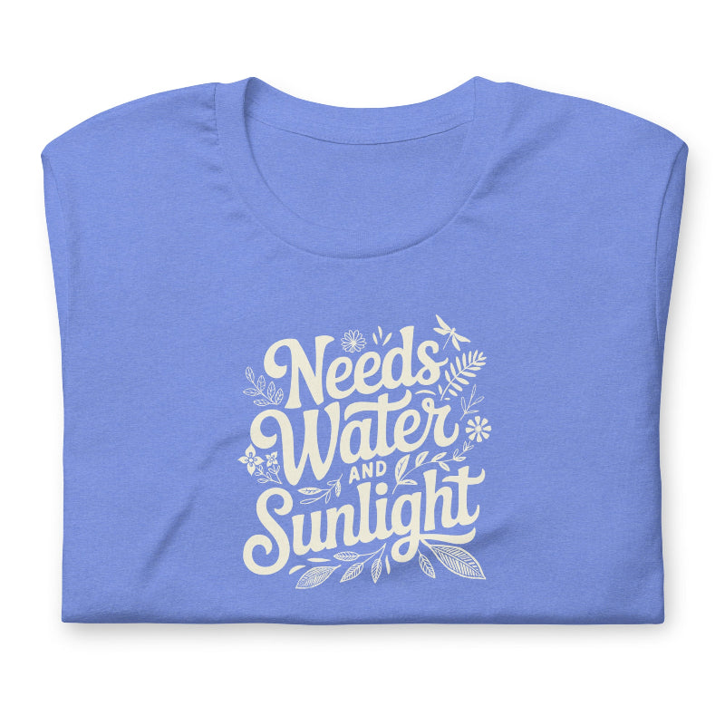 Bright columbia blue colored crewneck t-shirt with white words that say 'Needs Water and Sunlight' in script style text with dragonfly, flower and leaf illustrations around the words.