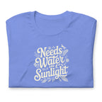 Bright columbia blue colored crewneck t-shirt with white words that say 'Needs Water and Sunlight' in script style text with dragonfly, flower and leaf illustrations around the words.