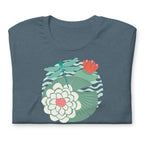Illustrated dragonfly hovering over a green lily pad with pink and white water lily flowers on a calm pond, printed on a soft gray-blue colored premium quality crewneck t-shirt. Shown folded for scale.